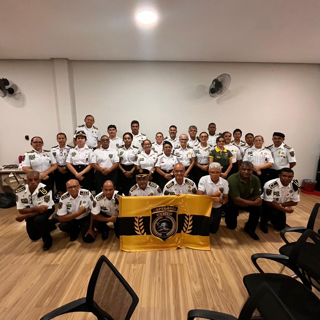 Oficiais UNICIM com a bandeira institucional em salão